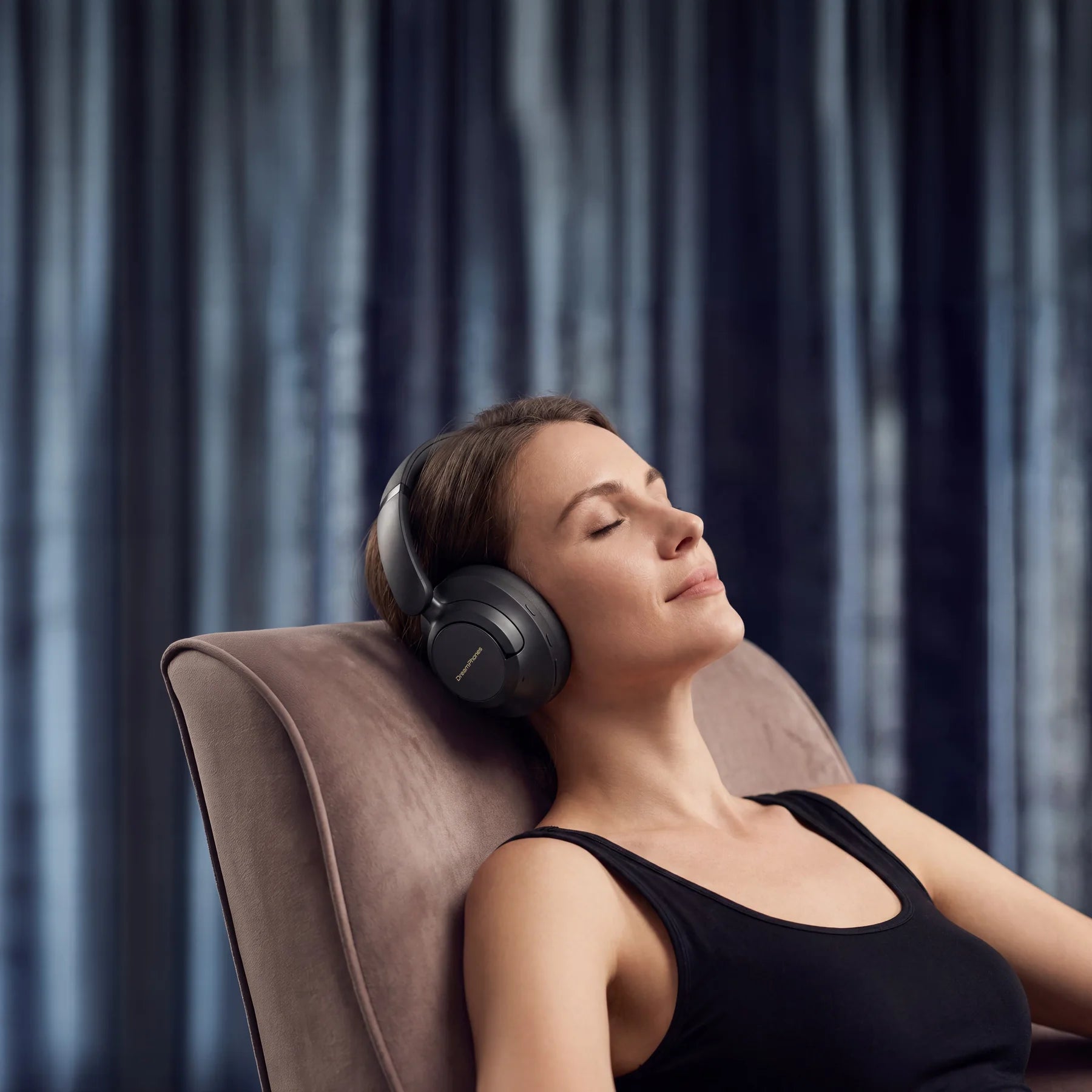 Woman seated with DreamPhones during an evening wind-down